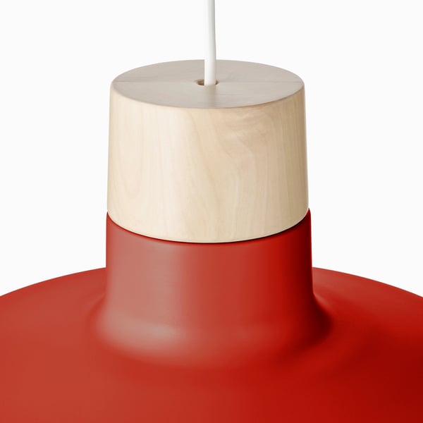 Modern pendant lamp with wooden top detail, red metal shade, emitting warm light.