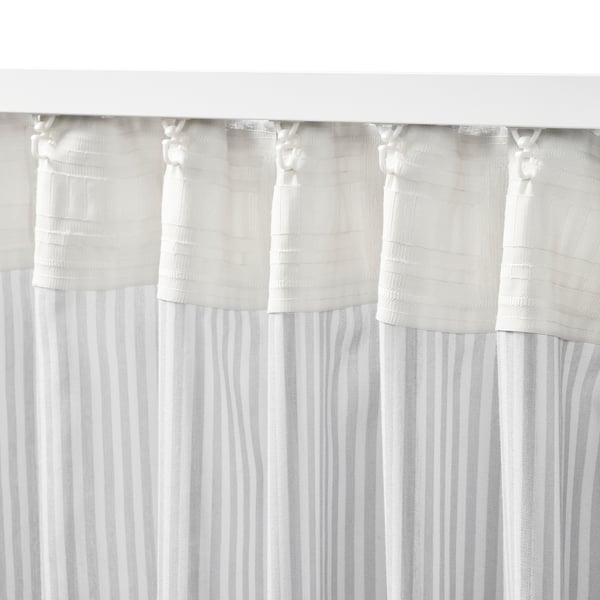 White striped curtains hang with pleats, offering privacy and light filtering. The heading tape holds them neatly, attached via clear curtain hooks.