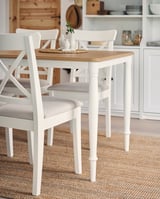 Modern white dining set with light grey cushioned chairs, wooden table top, and sturdy steel legs, perfect for cozy meals.