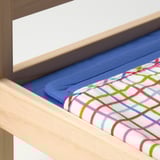 Wooden doll bed with blue mattress and multi-colored patterned blanket, showcasing high-quality craftsmanship and inviting texture.