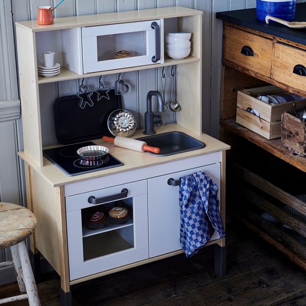 Play kitchen for kids, white with black details, includes sink, stove, oven, and accessories.