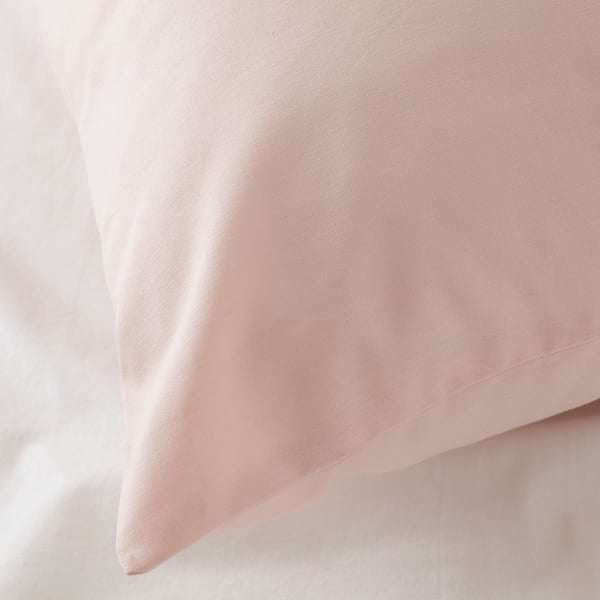 Close-up of soft, smooth light pink cotton pillowcase. Slight texture visible, showing quality fabric.