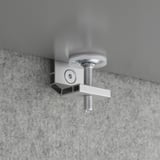 Metal desk clamp securely fastened with bolt mechanism, holding a gray surface, ensuring stability and durability.