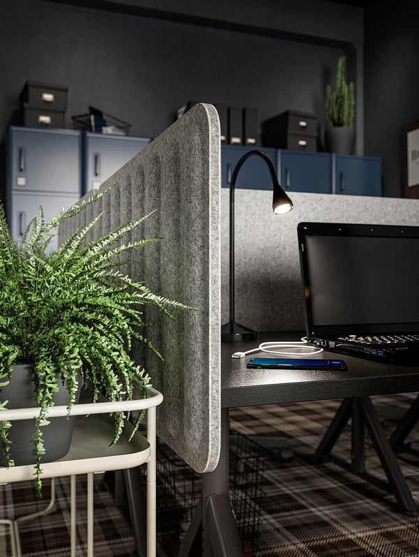 Modern workspace with EILIF gray sound-absorbing screen, laptop, keyboard, lamp, and potted plant.