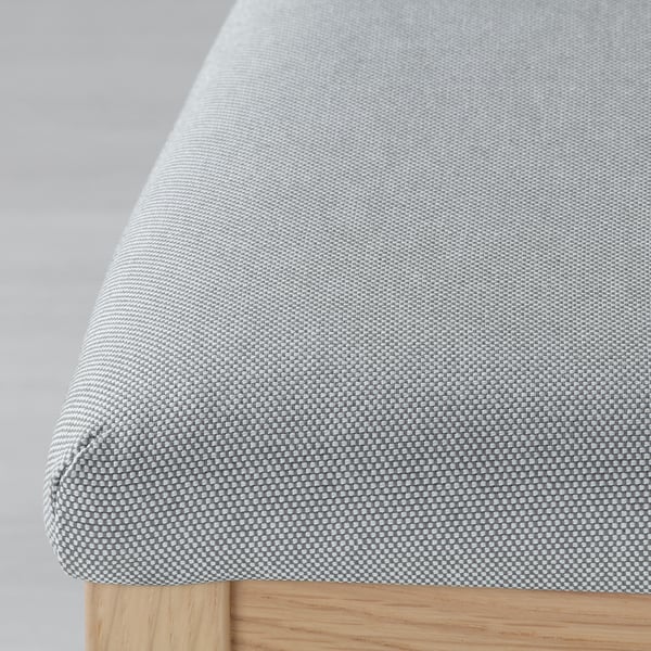 Modern upholstered chair with sleek wooden legs, featuring intricate fabric pattern and plush cushioning.