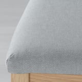 Modern upholstered chair with sleek wooden legs, featuring intricate fabric pattern and plush cushioning.