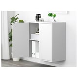 White EKET cabinet with open door, displaying shelf and items inside.
