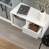 Wall-mounted storage with open drawer and shelf, vase with flowers.
