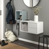 Minimalist entryway with white EKET wall storage, round mirror, denim jacket, backpack, and flowers.
