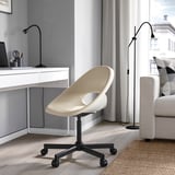 Modern home office with ELDBERGET chair, beige. Unique curved design, adjustable height, sturdy wheels. Positioned near desk with lamp, gray walls.
