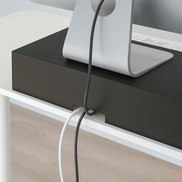 White monitor elevated on black bamboo stand with cable management, keeping workspace neat.