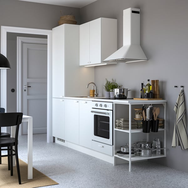 Modern white kitchen with white cabinets, stainless steel appliances, and organized countertops.