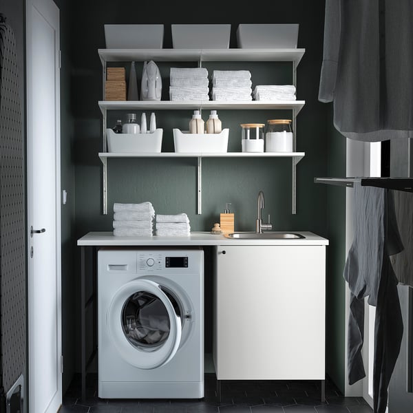Green laundry room with ENHET, washing machine & sink. Organized with shelves and gray curtains. Length: 148 characters