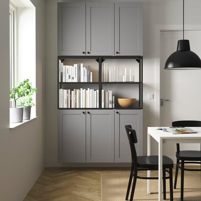 Modern grey ENHET storage with open & closed cabinets, books, table & chairs, ideal for compact spaces.