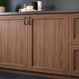 Sleek wooden kitchen cabinets with dark handles and a stylish countertop, ready for cooking and storage.