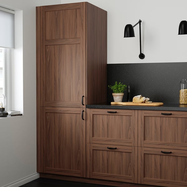 Modern kitchen with tall brown walnut ENKÖPING cabinets, sleek black countertop, and minimalist decor.