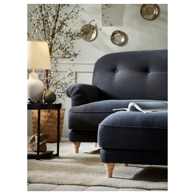 Cozy living room with dark blue sofa, lamp, vase, and candles.