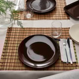Table set with FÄRGKLAR plates, cutlery, glasses on bamboo mats.