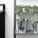 Metal shelf with two artificial plants in galvanized pots, suitable for indoor/outdoor use.
