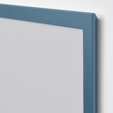 Blue picture frame leaning against a wall, displayed in a minimalist setting.