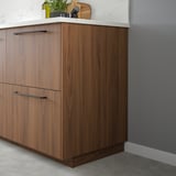 FÖRBÄTTRA walnut cover panel in modern kitchen, smooth, dark, sleek, matching cabinetry, tall.
