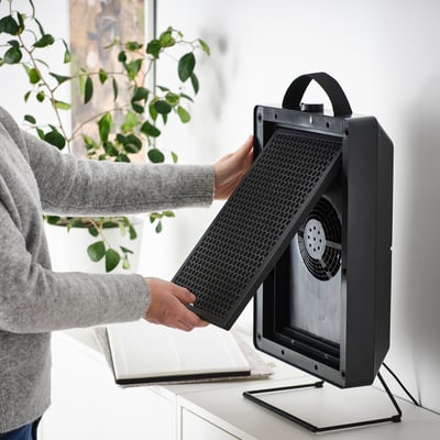 Person inserts FÖRNUFTIG filter into air purifier, removing gaseous pollutants and odors.