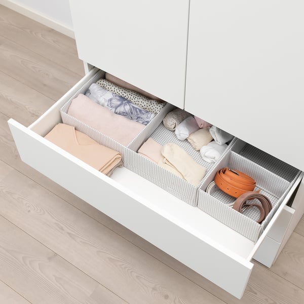 Dresser drawer with compartments holding folded clothes and accessories.