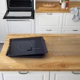 Kitchen counter with oven accessories: baking tray, cooling rack, and integrated meat probe, indicating versatile baking and cooking functions.
