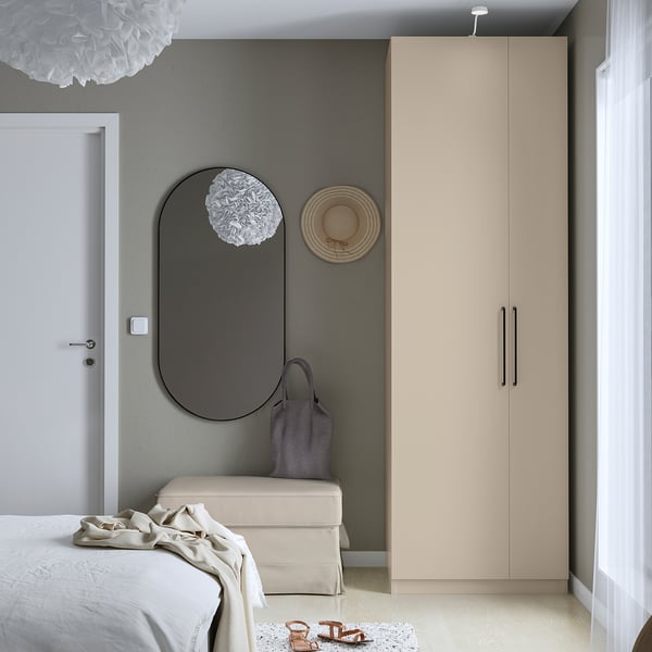 Modern bedroom, tall beige FORSAND wardrobe, mirror, basket, partially seen bed.
