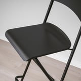 Black modern bar stool with curved seat and back, sturdy metal legs, shown against a light grey wall.