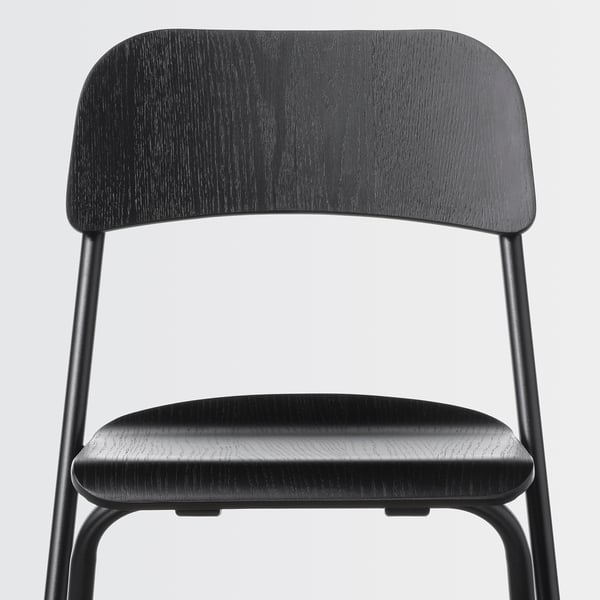 Modern black chair with curved back and seat, sturdy metal legs. Ideal for compact spaces.