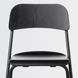 Modern black chair with curved back and seat, sturdy metal legs. Ideal for compact spaces.