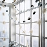 A festive silver paper garland decorates a window, its geometric shapes small compared to the window panes, creating a shining winter atmosphere.