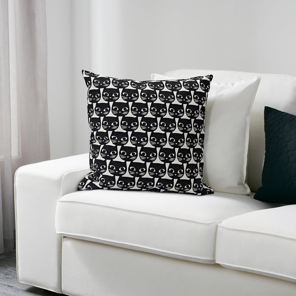 Decorative cat-themed cushion on white couch.