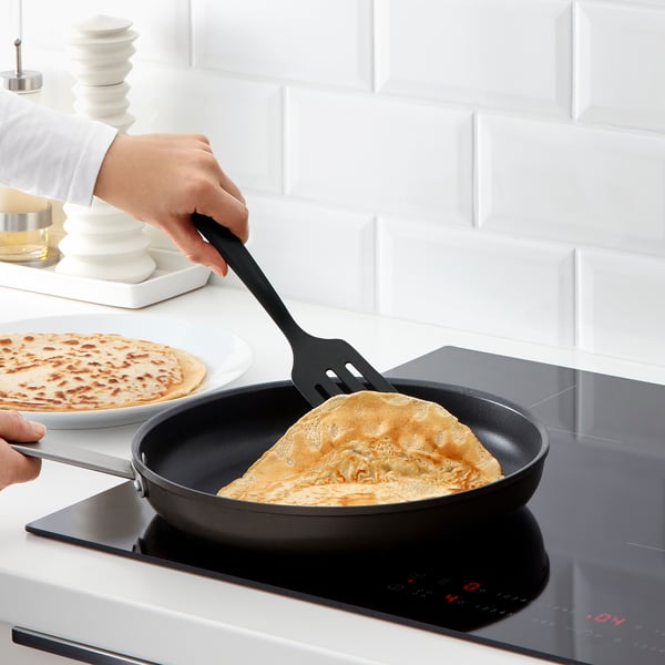 Person cooking pancakes with GNARP utensils and spatula on a non-stick skillet.
