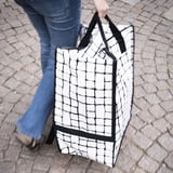 Large white bag with black handles and grid pattern, good for carrying or backpacking.