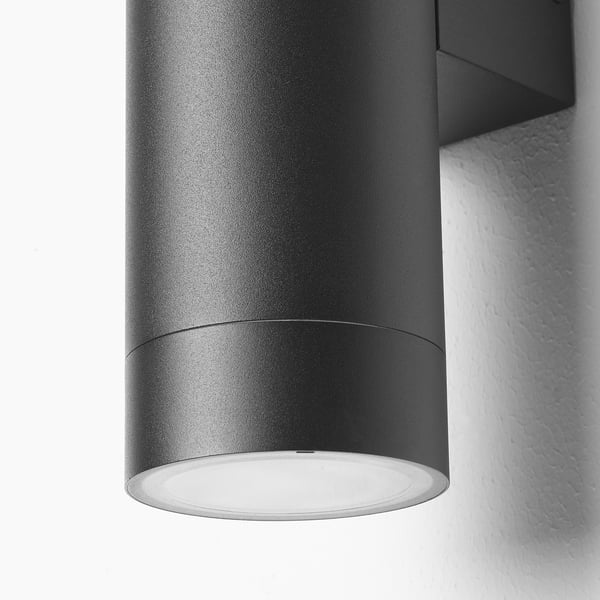 Modern outdoor wall lamp featuring sleek, dark cylindrical design and warm, glowing light.