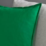 A close-up of a green cushion cover with visible stitching detail, showcasing its texture and quality.