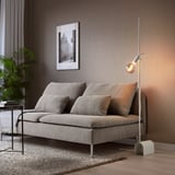 Modern living room with HÅRSLINGA lamp illuminating sofa, side table with plant, books, and black & white wall art.