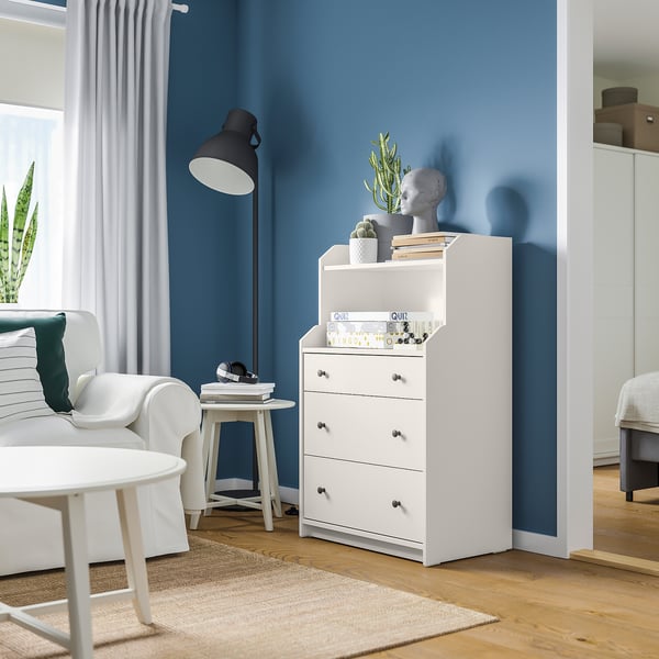 Modern room with white HAUGA chest, blue wall, plants, white curtains, and white furniture.