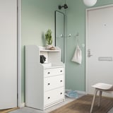 Modern entryway with white HAUGA storage chest, green cactus, mirror, and door.