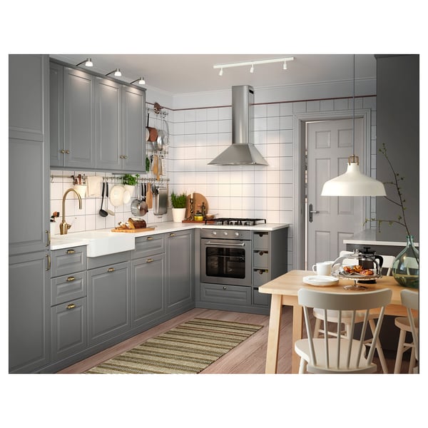 Modern grey kitchen with wooden floor, white table, and hanging lamps. Has a HAVSEN sink and traditional stove.