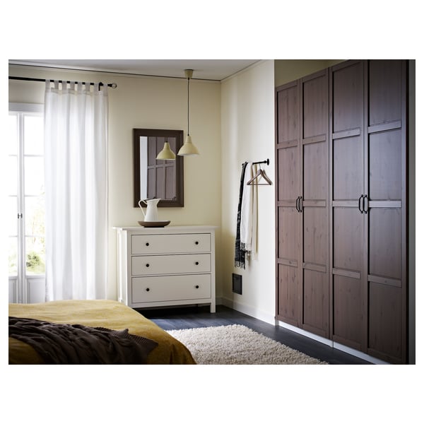 A modern bedroom with white dresser, mirror, yellow lights, and dark wooden closet.