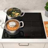 Modern kitchen with HÖGKLASSIG induction hob, cooking vegetables and stew.