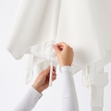 Image depicts hands adjusting straps on a HÖGÖN hanging parasol, ensuring secure attachment before use.
