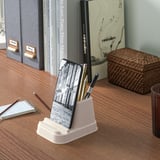 Phone & pen holder on desk with books and basket.