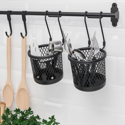 Wall-mounted storage with kitchen tools. Metal baskets and hanging utensils.