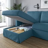 A blue sofa with a lift-up chaise longue revealing storage filled with blankets and a box.