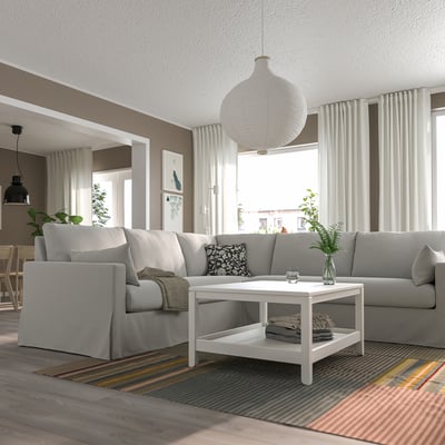 L-shaped sectional sofa in bright room with rug, coffee table, & windows.