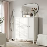Modern entryway with white IDANÄS cabinet, mirror, lamps, flowers, coat hooks, and light pink curtains.